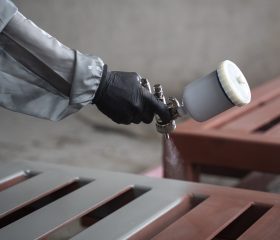 worker-spraying-powder-paint-from-gun-side-view